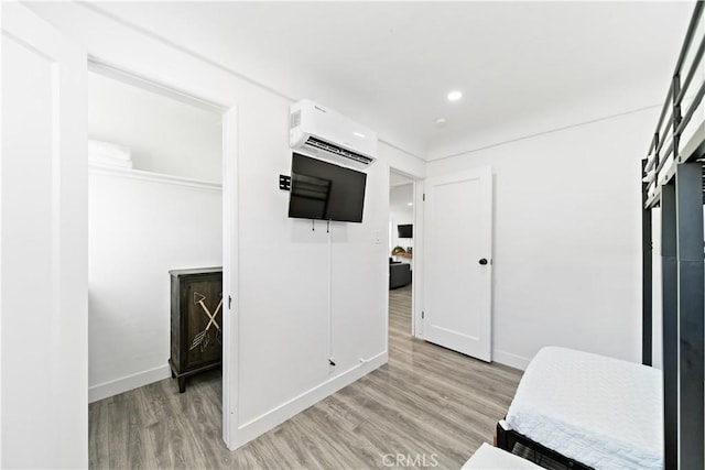 bedroom with recessed lighting, baseboards, a wall mounted AC, and light wood-style floors