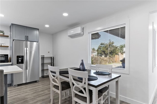 dining space with recessed lighting, baseboards, light wood-style flooring, and a wall unit AC