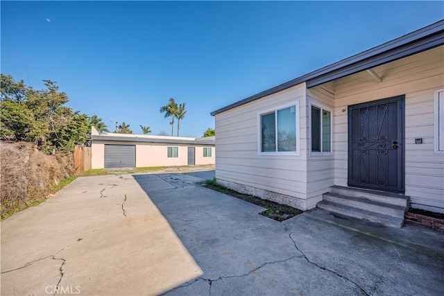 exterior space with entry steps, a detached garage, and fence