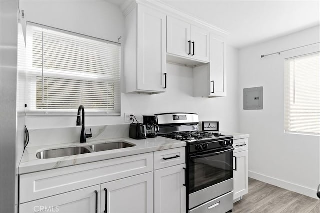 kitchen with gas range, white cabinets, a healthy amount of sunlight, and a sink