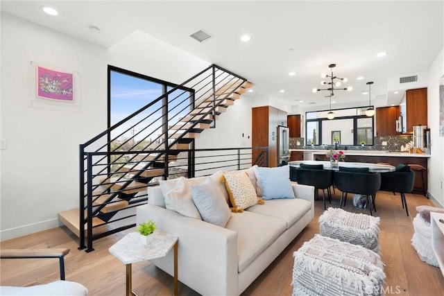 living room with light wood-type flooring, visible vents, recessed lighting, baseboards, and stairs