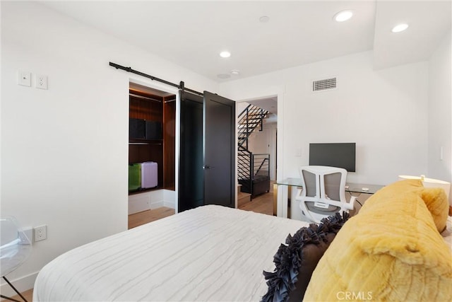 bedroom featuring recessed lighting, visible vents, a barn door, and wood finished floors