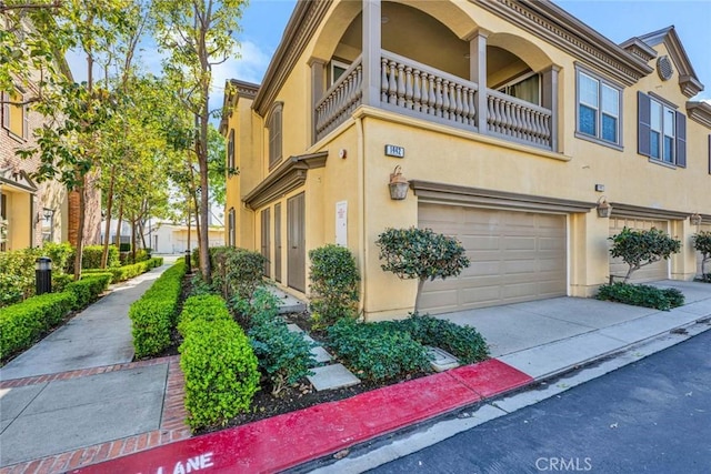 view of side of property with a balcony, stucco siding, driveway, and a garage