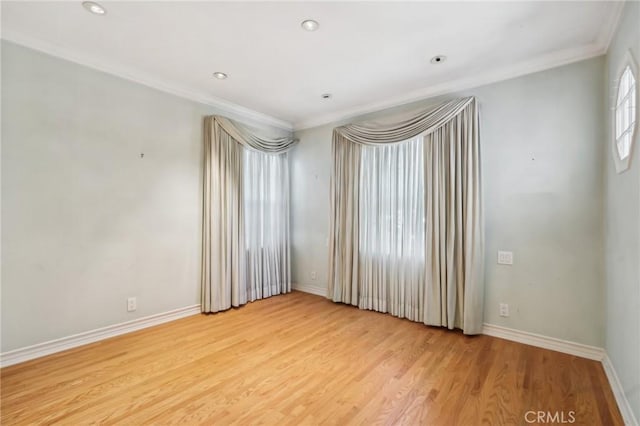 empty room featuring light wood finished floors, recessed lighting, baseboards, and ornamental molding