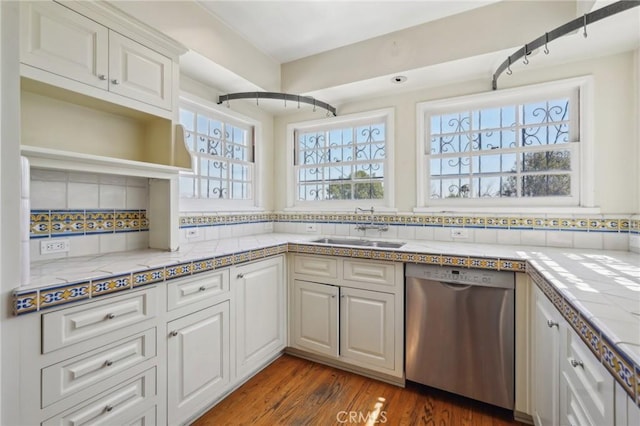 kitchen with dishwasher, light countertops, wood finished floors, white cabinets, and a sink