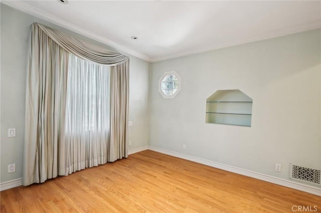 empty room with crown molding, baseboards, visible vents, and light wood-type flooring