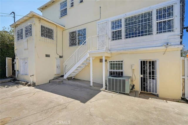 rear view of property featuring central air condition unit, a patio, and stucco siding