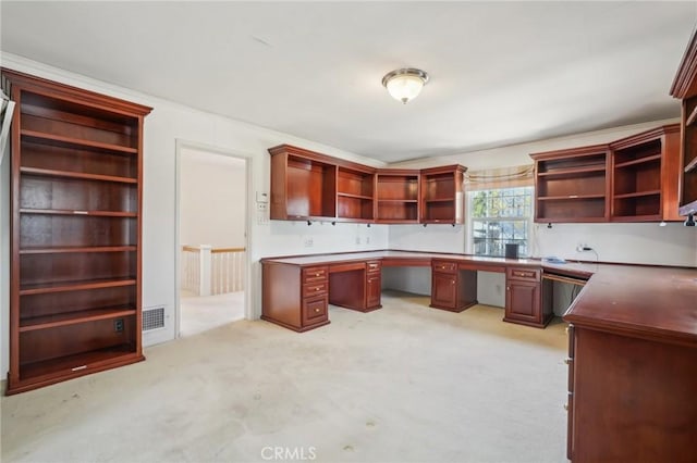 unfurnished office featuring visible vents, light colored carpet, and built in study area