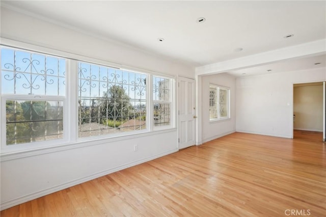 spare room with baseboards and light wood finished floors