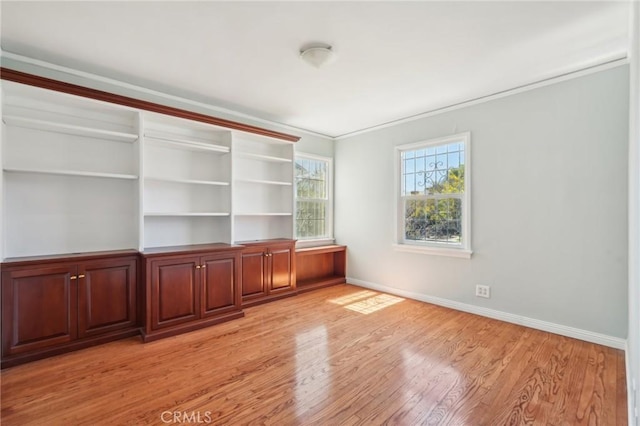 empty room with baseboards, ornamental molding, and light wood finished floors