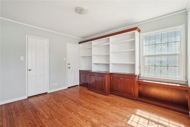 empty room with light wood-type flooring, baseboards, and ornamental molding