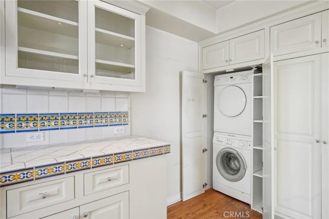 washroom featuring laundry area, stacked washer / drying machine, and light wood finished floors