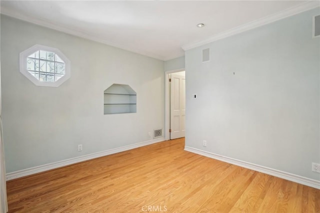 unfurnished room with visible vents, light wood-style flooring, crown molding, and baseboards