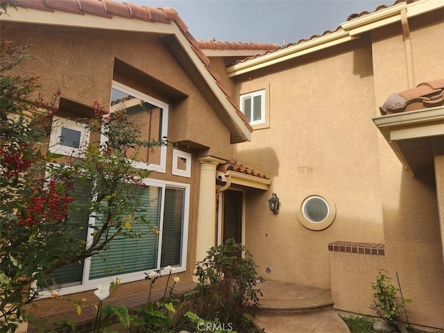 property entrance featuring stucco siding and a tiled roof