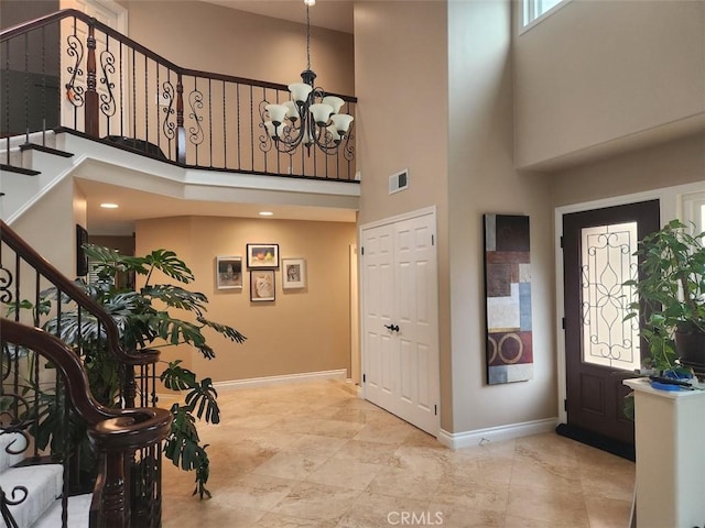 foyer with stairway, visible vents, baseboards, a high ceiling, and a notable chandelier