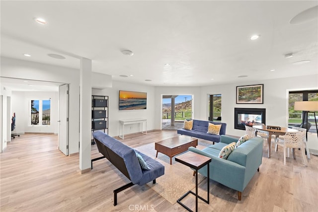 living room with a multi sided fireplace, recessed lighting, light wood-style flooring, and baseboards