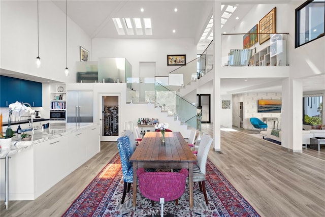 dining space with stairway, light wood-style flooring, built in features, and a towering ceiling