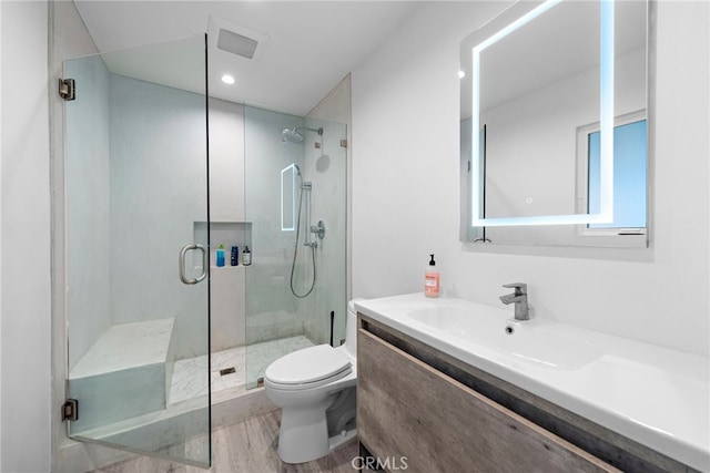 full bath featuring a stall shower, toilet, vanity, and wood finished floors