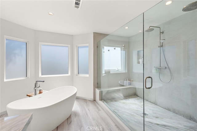 bathroom with a freestanding tub, wood finished floors, and a shower stall