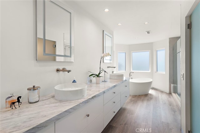 bathroom featuring a stall shower, wood finished floors, visible vents, and a sink