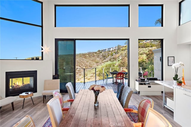 dining area featuring wood finished floors, a multi sided fireplace, and a towering ceiling