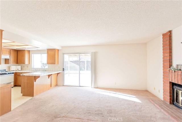 unfurnished living room featuring a textured ceiling, a brick fireplace, and light carpet