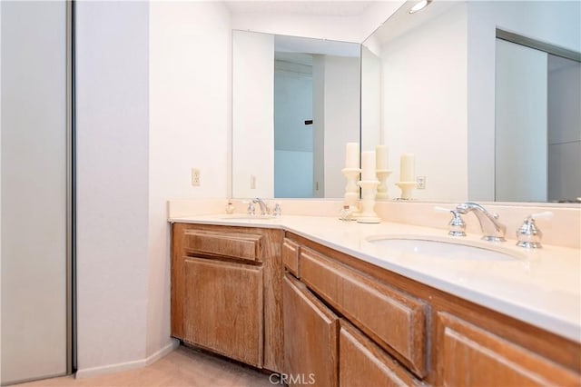 bathroom with double vanity, baseboards, and a sink