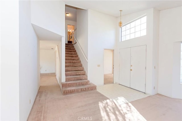 carpeted foyer with stairway and a high ceiling