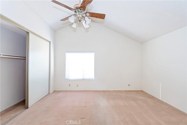 unfurnished bedroom with a closet, carpet flooring, ceiling fan, and vaulted ceiling