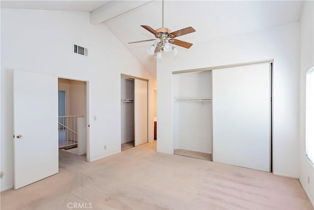 unfurnished bedroom featuring visible vents, multiple closets, high vaulted ceiling, beam ceiling, and light carpet