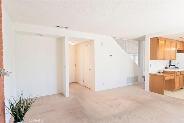 living area with a textured ceiling, stairway, visible vents, and light carpet