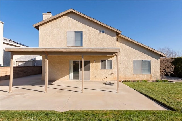 back of property with a patio area, a lawn, a chimney, and stucco siding