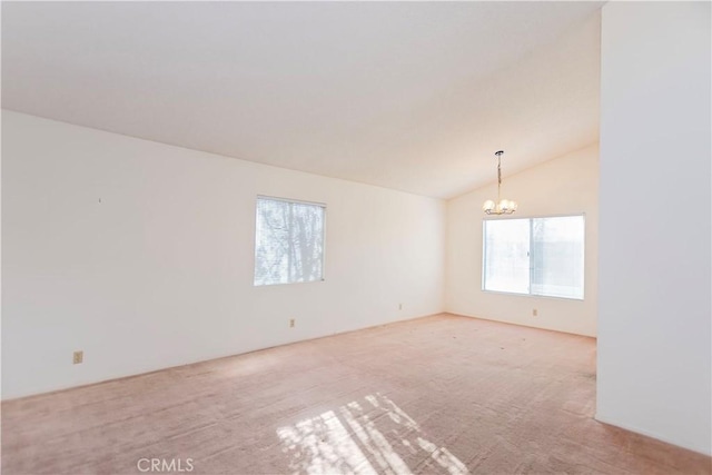 carpeted empty room featuring a chandelier and vaulted ceiling