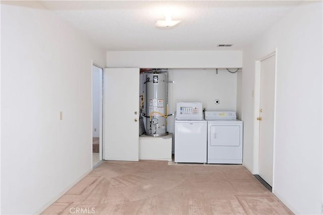 clothes washing area featuring gas water heater, visible vents, a textured ceiling, and washer and clothes dryer