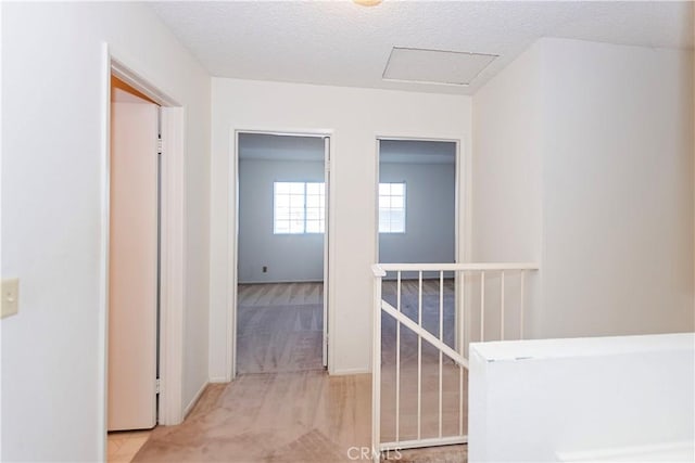 hall featuring an upstairs landing, attic access, and a textured ceiling