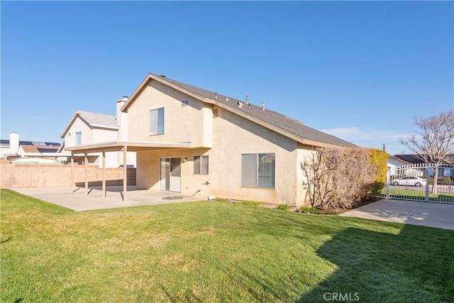 back of property featuring stucco siding, a patio, a lawn, and fence