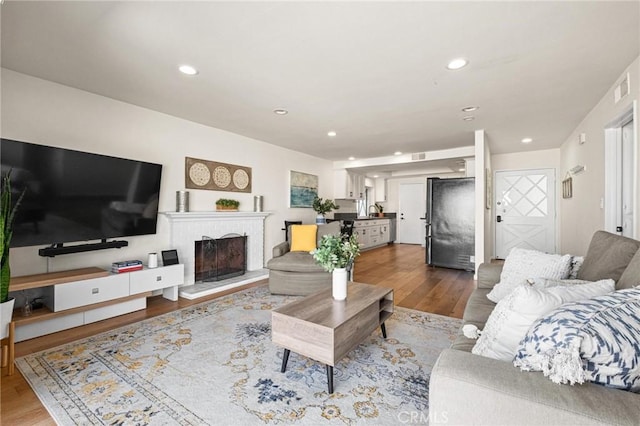 living area featuring visible vents, recessed lighting, a brick fireplace, and wood finished floors