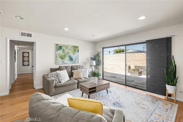 living area with recessed lighting, visible vents, baseboards, and wood finished floors