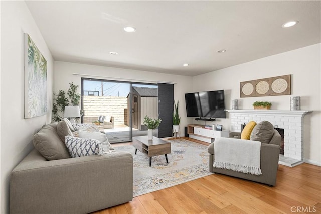 living room with recessed lighting, light wood-type flooring, baseboards, and a fireplace