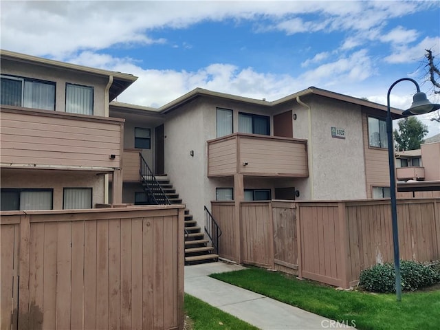 view of home's community featuring stairway and fence