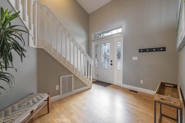 entrance foyer featuring visible vents, light wood finished floors, baseboards, and stairway