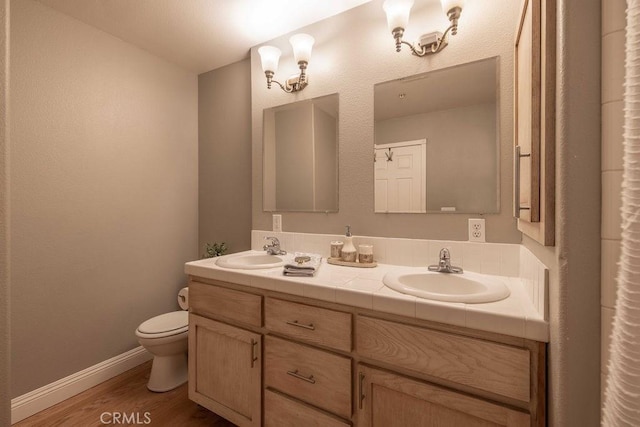 bathroom featuring a sink, toilet, wood finished floors, and double vanity