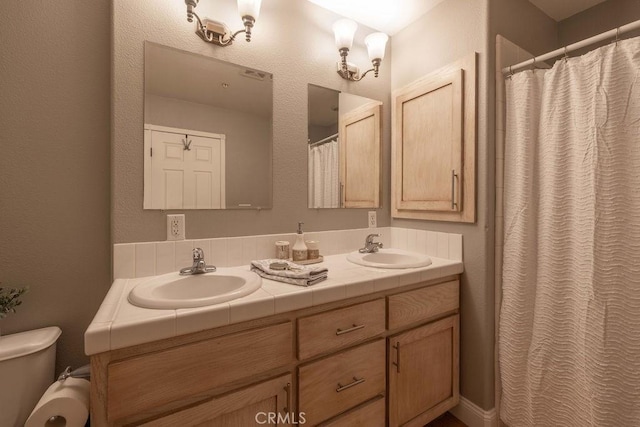 full bathroom featuring a sink, curtained shower, toilet, and double vanity