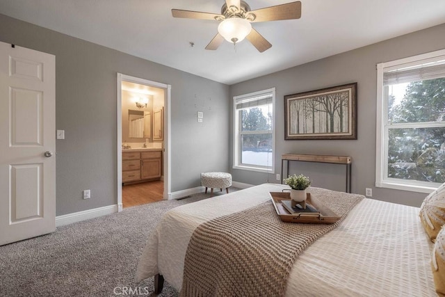 carpeted bedroom with connected bathroom, baseboards, and ceiling fan