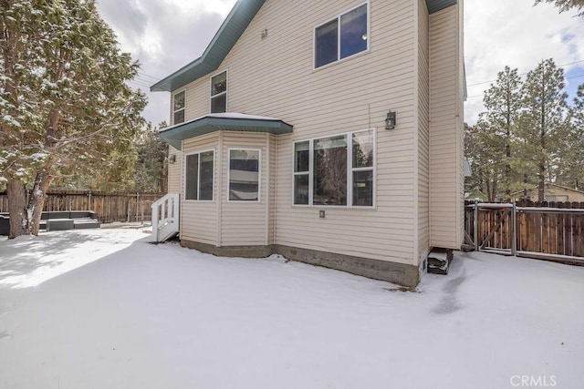 snow covered back of property featuring fence