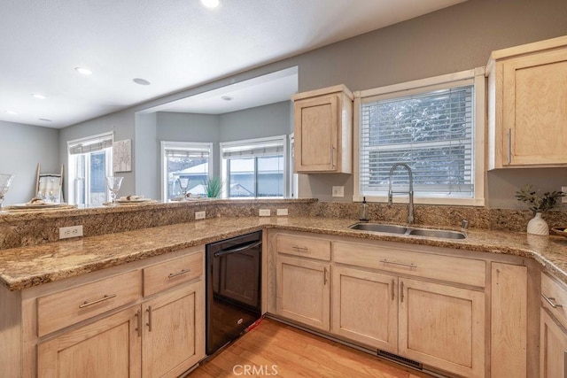 kitchen with plenty of natural light, light brown cabinets, light stone countertops, and a sink