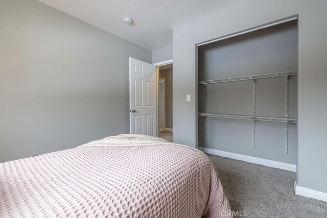 carpeted bedroom featuring a closet and baseboards