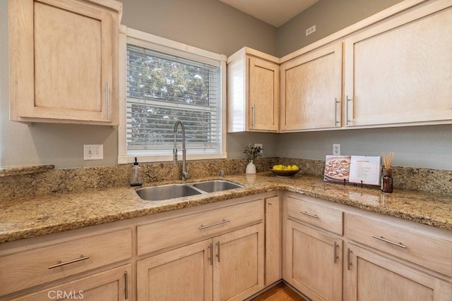 kitchen featuring a sink, light stone counters, and light brown cabinetry