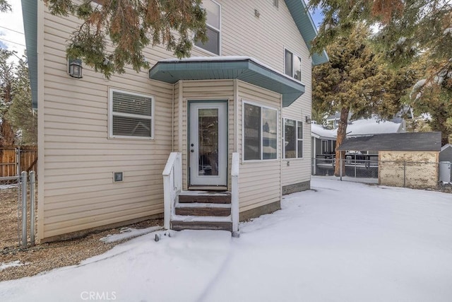 snow covered back of property with entry steps and fence