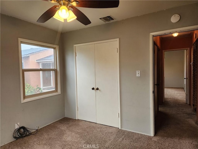 unfurnished bedroom with a closet, visible vents, ceiling fan, and carpet